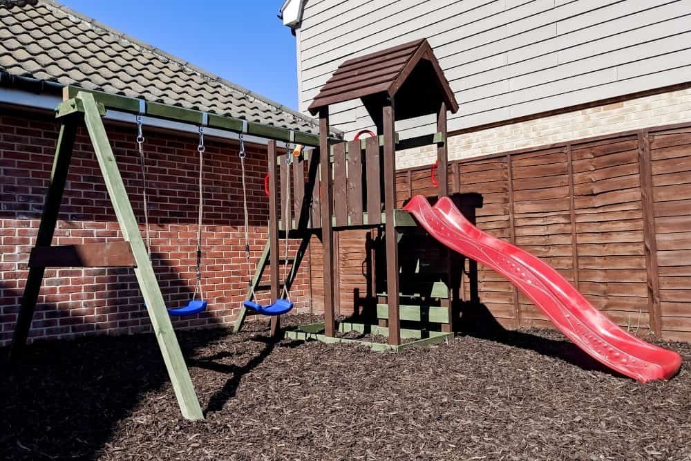 A wooden climbing frame sitting on play bark