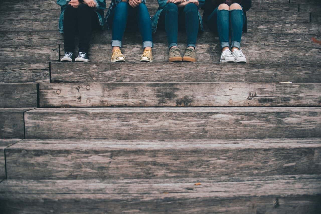 life skills for teens - four teenagers sitting on wooden steps