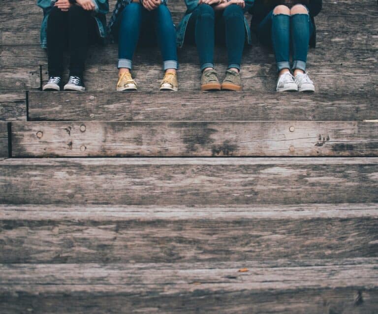 life skills for teens - four teenagers sitting on wooden steps