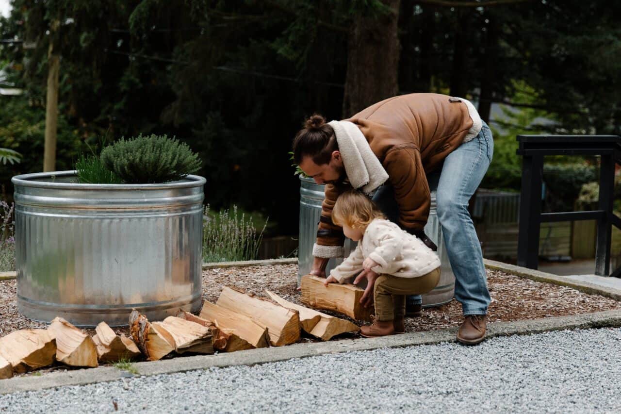 father and daughter putting firewood on ground