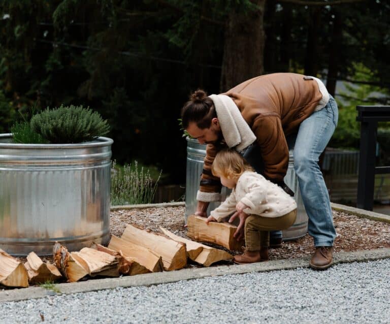 father and daughter putting firewood on ground