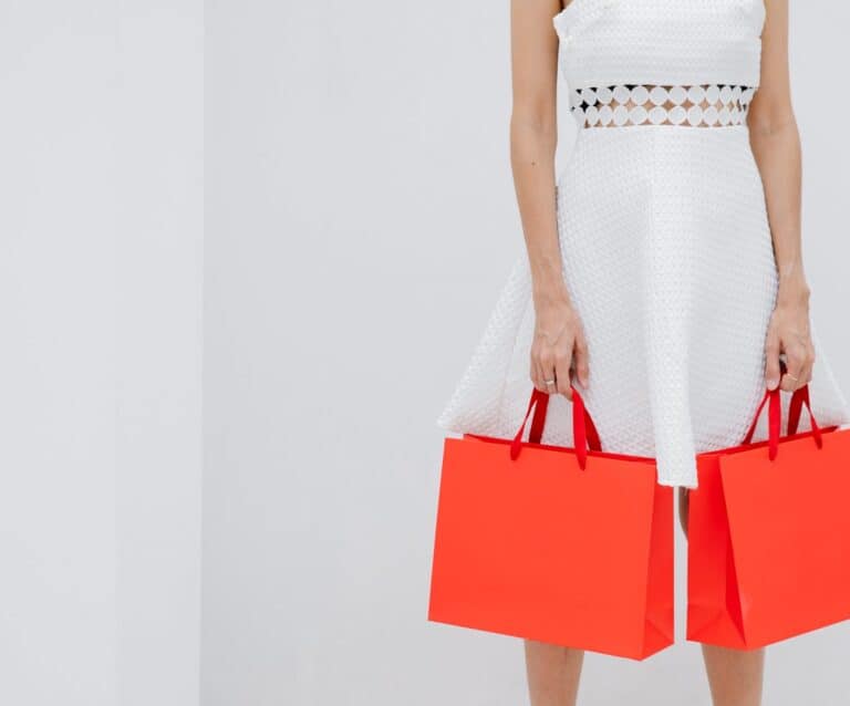 crop unrecognizable woman carrying red shopping bags in studio