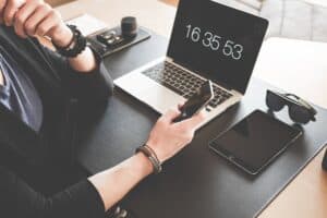 How To Take Your Business Into The Digital World - woman using a smartphone while fronting a macbook pro and black ipad