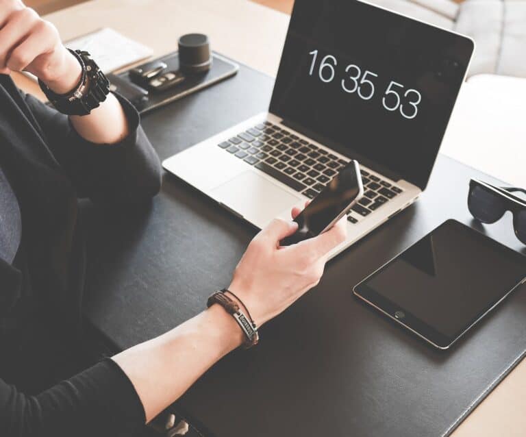 How To Take Your Business Into The Digital World - woman using a smartphone while fronting a macbook pro and black ipad