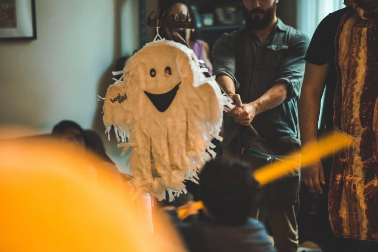 person holding stick in front of white ghost pinata