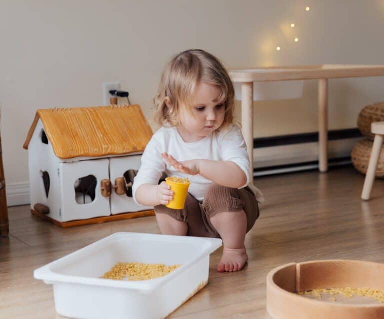 girl holding yellow plastic cup full of macaroni