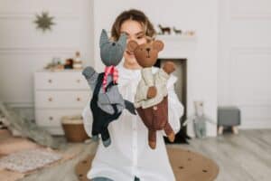 a woman holding two plush toy puppets