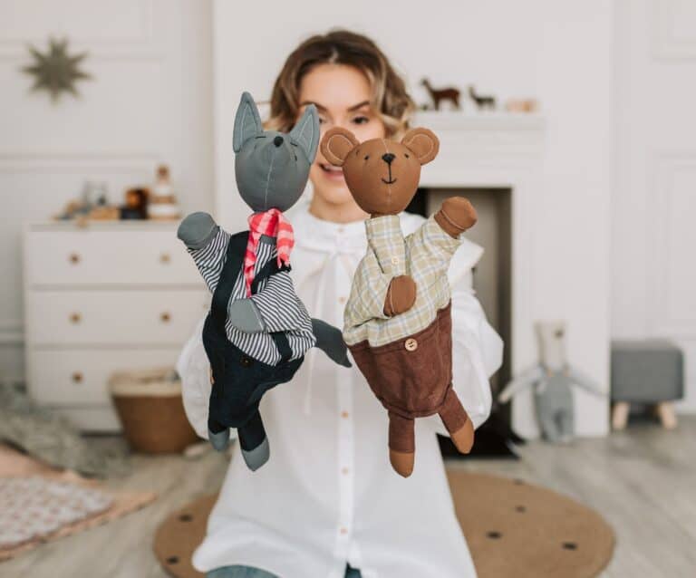 a woman holding two plush toy puppets