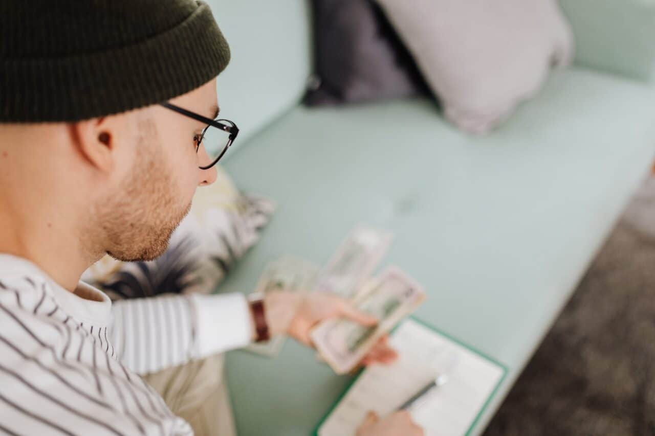 man in black beanie hat holding money - Practical tips to manage your money