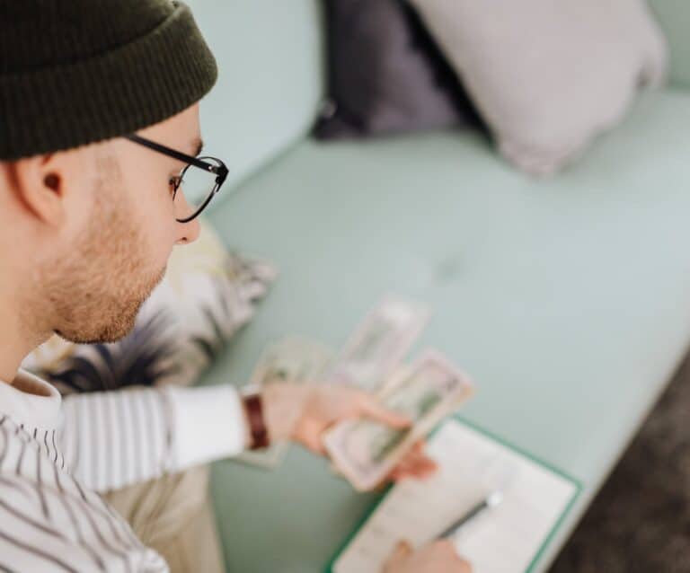 man in black beanie hat holding money - Practical tips to manage your money