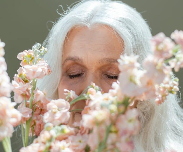 elderly woman smelling pink flowers