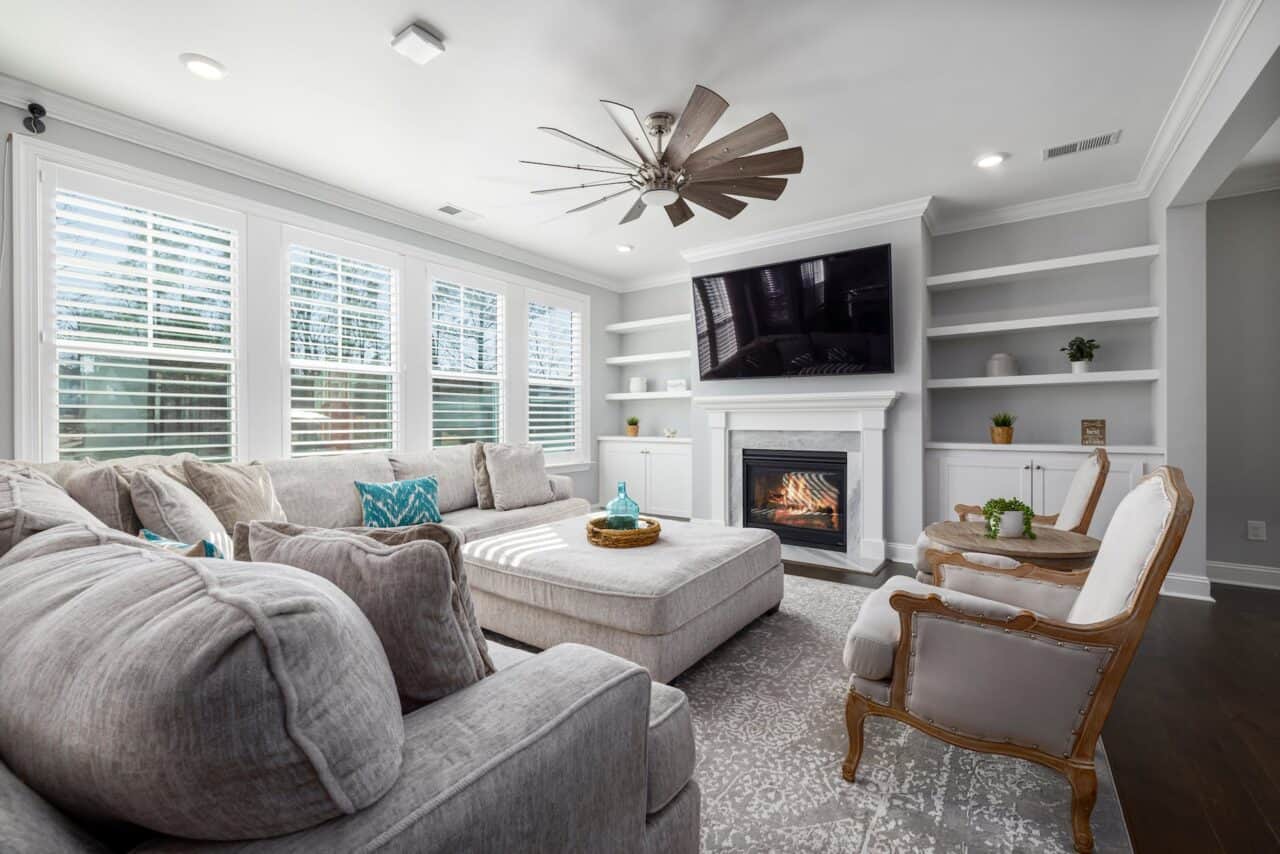 a ceiling fan in a living room with a gray couch