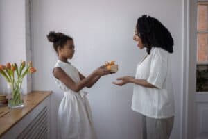 a girl giving her mother a present for mother s day - What to Get Your Cool Mom for Mother's Day