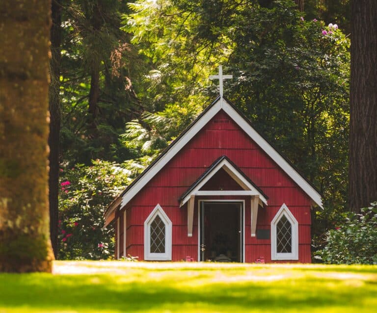 red chapel on grassy field with trees