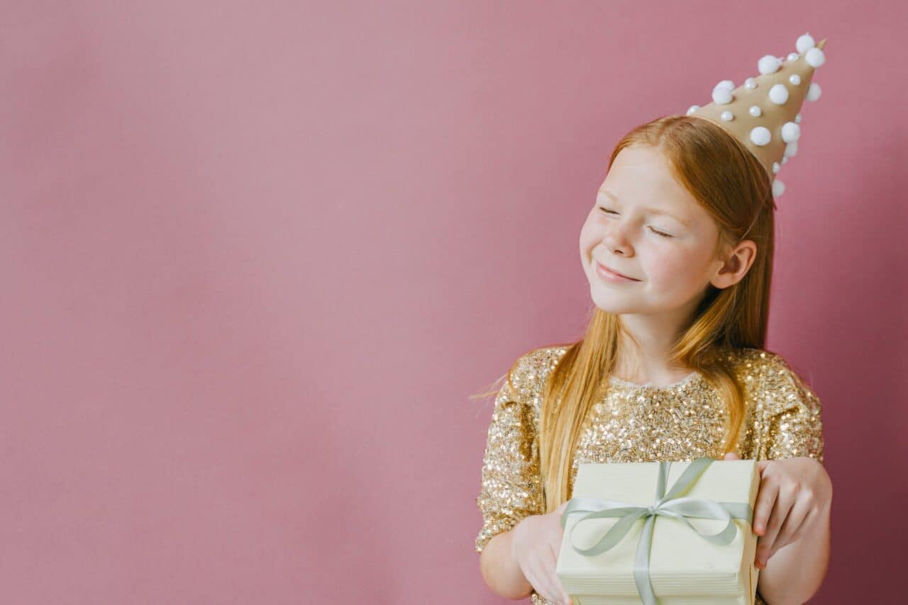 smiling girl in golden dress holding her birthday present