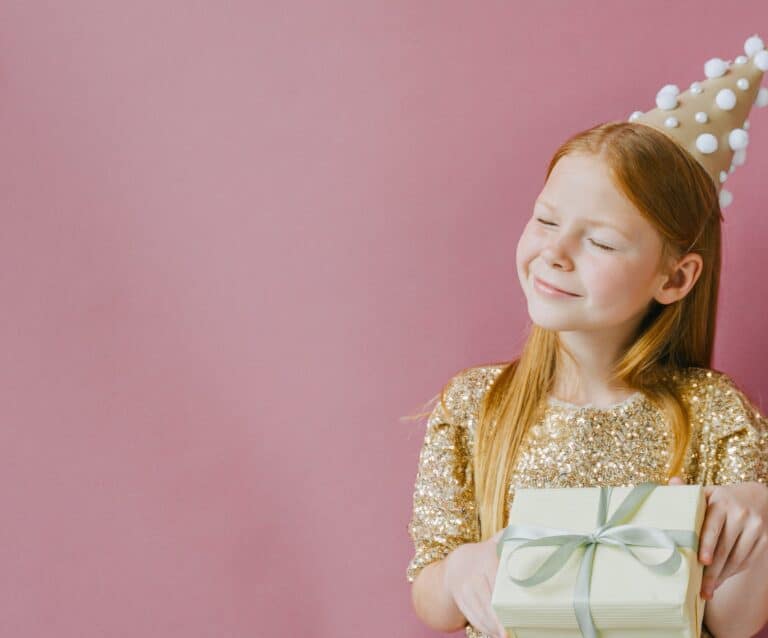 smiling girl in golden dress holding her birthday present