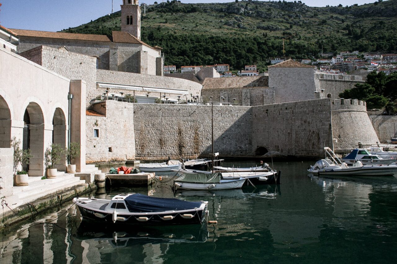 boats on calm sea water and stone fort