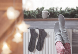 Woman warming up with feet on heater. Space-Saving Solutions with Radiators