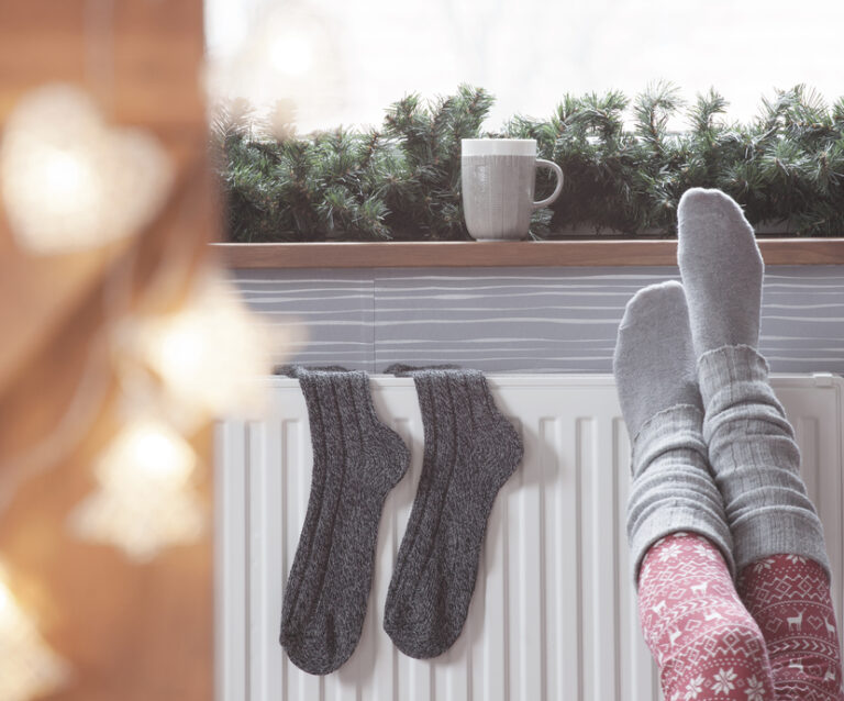 Woman warming up with feet on heater. Space-Saving Solutions with Radiators